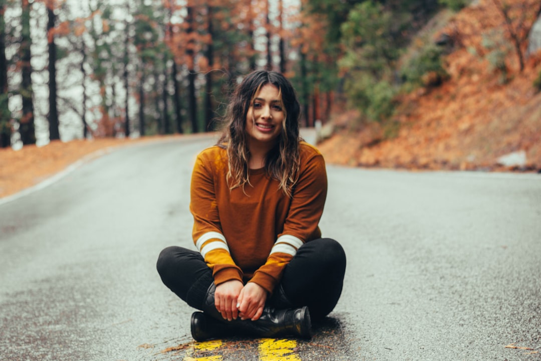 Smiling cross-legged on road by Hispanic Month woman sitting on concrete road