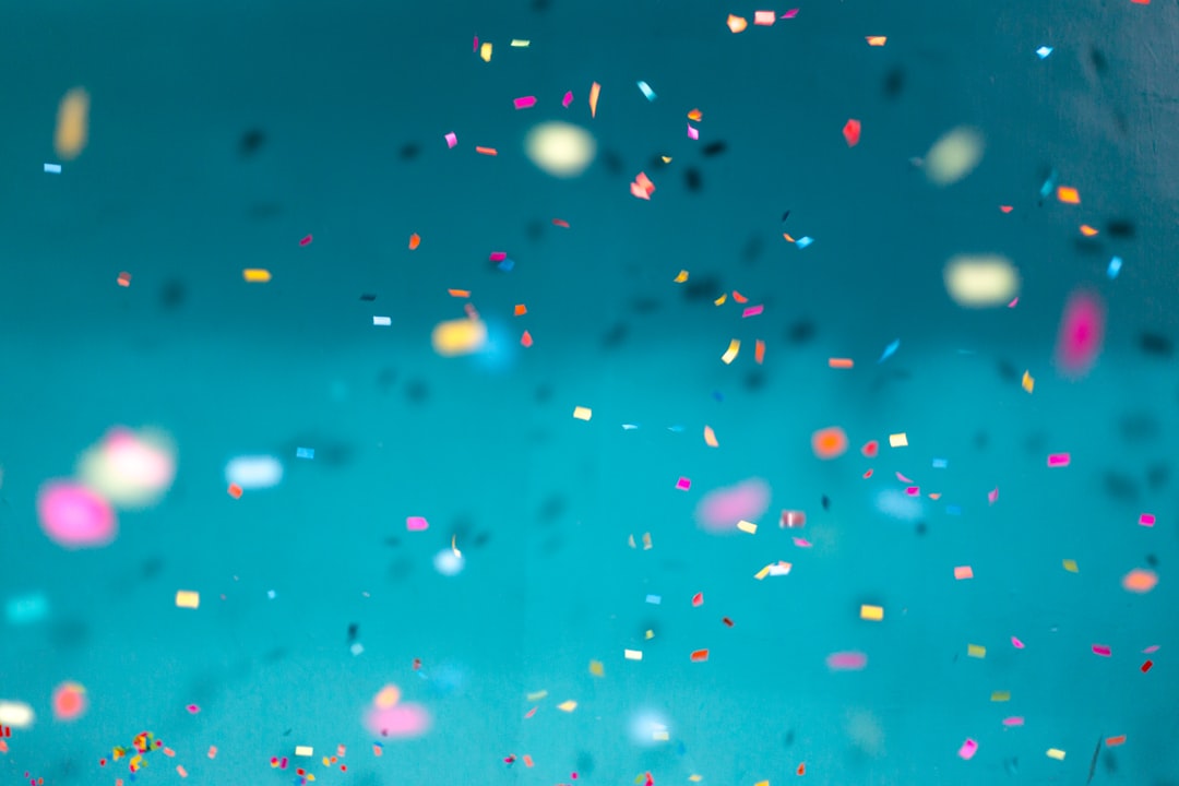 Colorful confetti falling down with a teal background by Hispanic Month selective focus photography of multicolored confetti lot