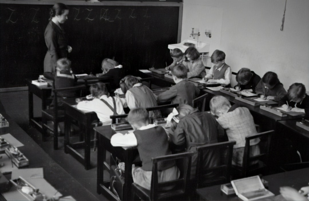 Glance into a classroom, 1935 by Hispanic Month grayscale photography of teacher standing near chalkboard and children sitting on chairs