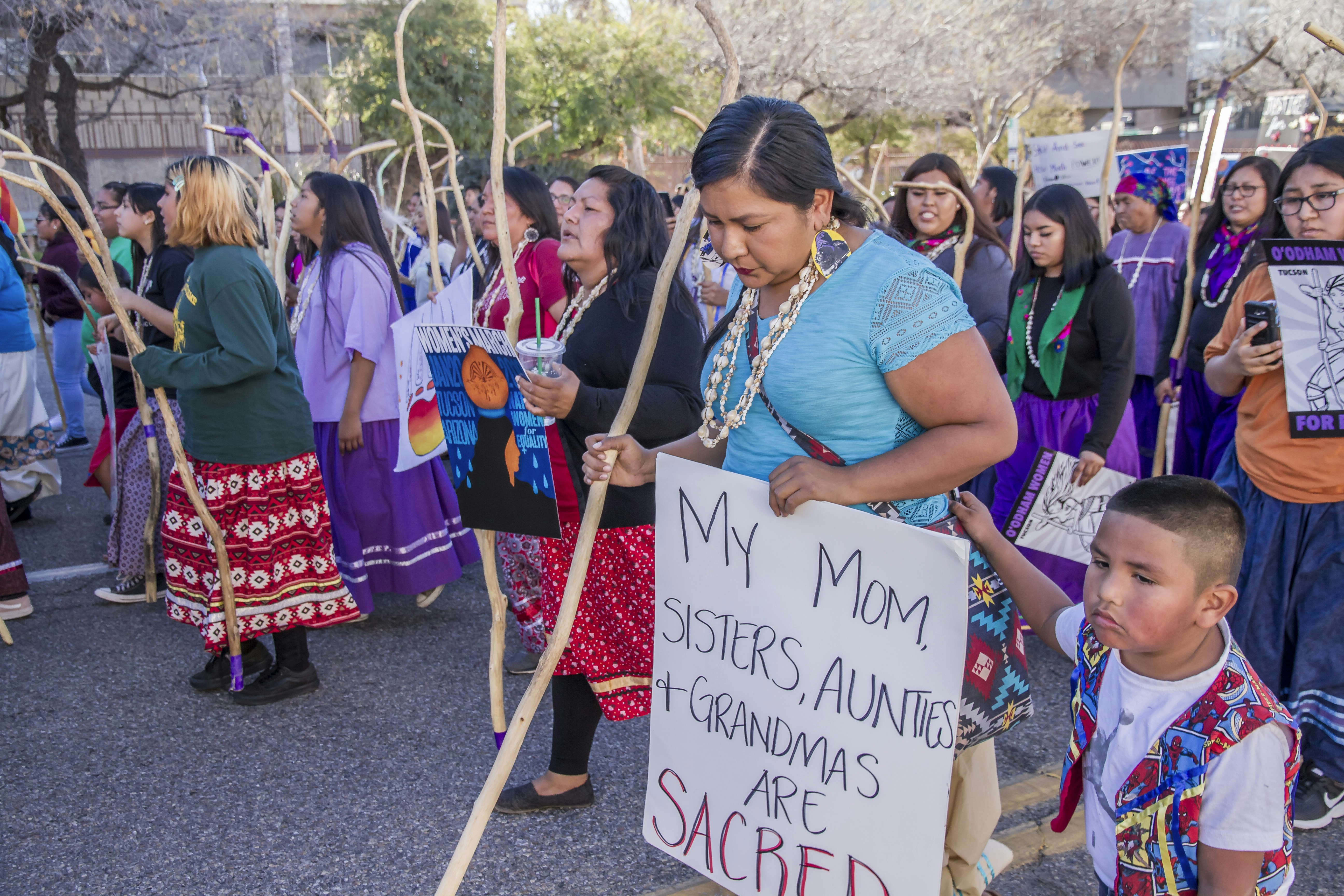 Tohono Indian Women led the Tucson 2019 Women’s March with a show of strength, resilience and power. This woman’s sign said: My Mom, Sisters, Aunties and Grandmas are sacred. Her son was by her side.
International Women’s Day by Hispanic Month group of women walking at the street protesting about woman's right